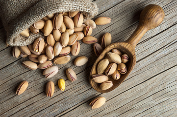 Pistachio in nutshell on wooden rustic backdrop in wooden shovel, composition of Top view pistachios great for healthy and dietary nutrition. Concept of nuts