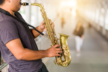 A street musician plays the saxophone with blurry people