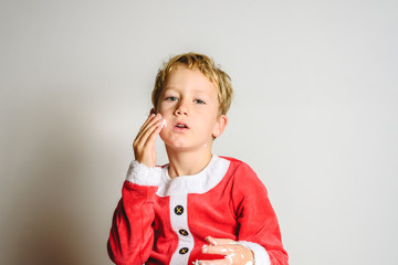 Child in Santa costume playing with shaving cream to have fun at Christmas.