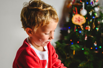 Child in Santa costume playing with shaving cream to have fun at Christmas.
