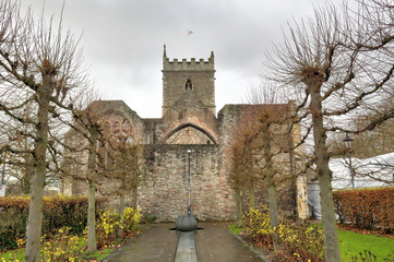 The exterior of the abandoned rumbled Saint Peter's Church in the Castle Park, with pointed arch windows and bell tower, in Bristol, United Kingdom