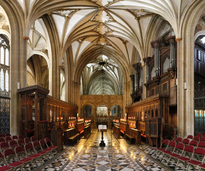 The main choir in the central nave of the Bristol Cathedral, with pointed Gothic arch vaults and wooden benches in South West England, United Kingdom