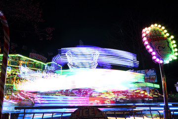 Colorful light blur and stripes due to motion of a carousel by night in the Gorsedd Gardens...