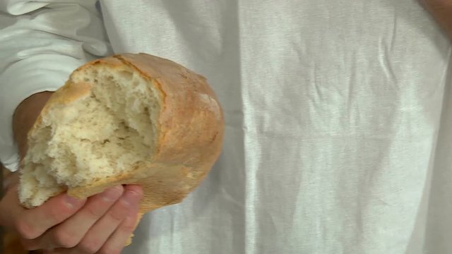 Men's hands break a loaf of fresh bread