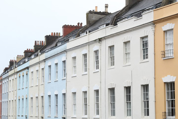 White, blue and rose terrace houses with sash hung windows, black roofs and chimney stacks in a cloudy day in Bristol, United Kingdom