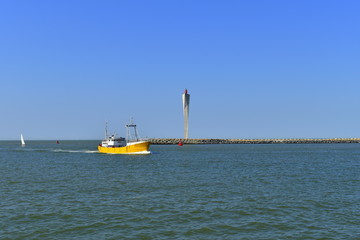 yellow fishing boat sailing to harbour