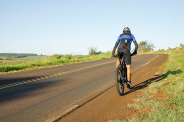 Ciclista pedalando no asfalto de manhã.