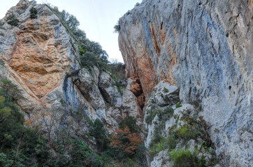 The Foz de Escalete breach on the high rocky escarpments due to water erosion next to La Peña lake, with trees on rocks, at sunset, in Aragon, Spain
