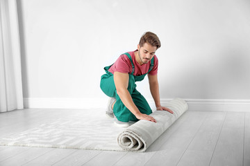 Man rolling out new carpet flooring indoors