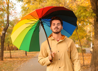 Young man with bright umbrella walking in park