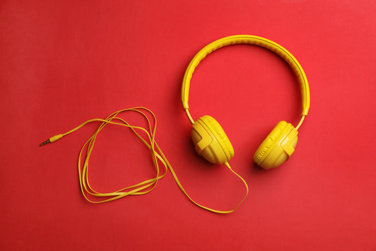 Stylish modern headphones with earmuffs on color background, top view
