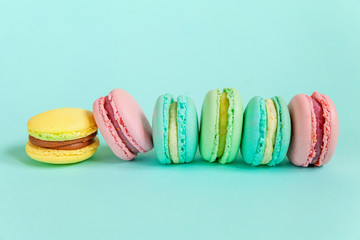 Sweet almond colorful pink blue yellow green macaron or macaroon dessert cake isolated on trendy blue pastel background. French sweet cookie. Minimal food bakery concept. Flat lay top view copy space