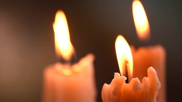 Candle flame on a dark background. Candle light closeup. Melted wax candles burning at night. Slow motion 4K UHD video footage. 3840X2160