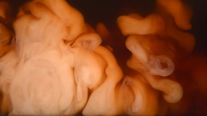 Abstract milk in coffee or tea background. Backdrop of dropping cream in black coffee, Cream swirling in coffee. Slow motion 4K UHD video footage. 3840X2160