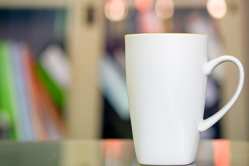 White ceramic glass placed on the desk, the background blurred.