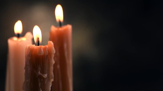 Candle flame closeup on a dark background. Candle light border design. Melted wax candles burning at night. Slow motion 4K UHD video footage. 3840X2160