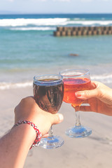 Two hands holding glasses with wine on sea background. Female and male hands with wine glasses.