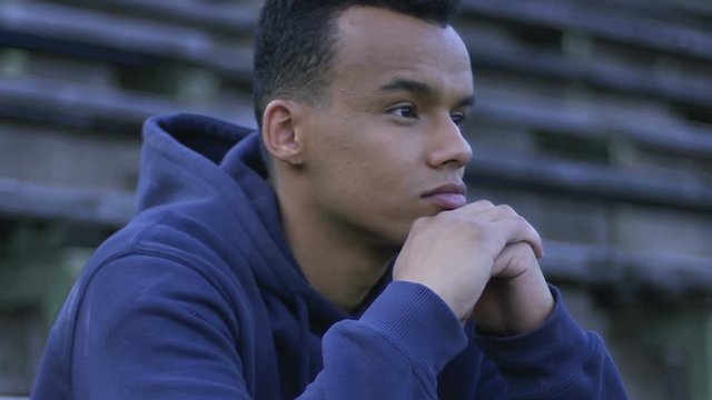 African american guy sitting on bench, disqualification from school sports team