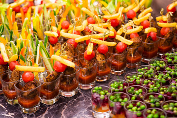 meat snacks with vegetables in a glass cup on a tray