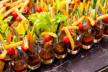 meat snacks with vegetables in a glass cup on a tray