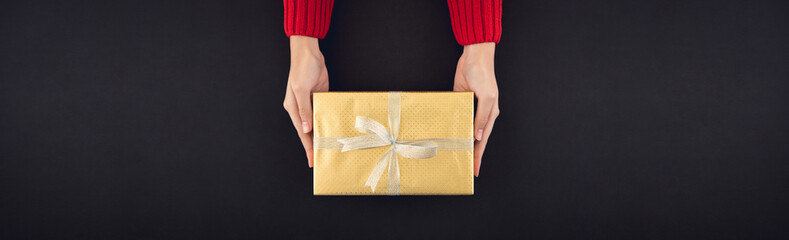 Woman hands giving christsmas gift box wrapped with shiny golden paper