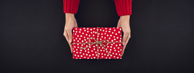 Woman hands giving christsmas gift box wrapped with shiny golden paper
