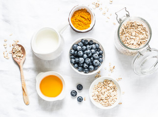 Ingredients for cooking coconut milk turmeric blueberry oatmeal porridge on a light background, top view. Gluten free, vegetarian food concept
