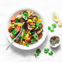 Marinated eggplant, sweet tomato and cilantro mediterranean style salad on light background, top view. Vegetarian food concept