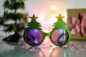 Christmas tree glasses and candy cane confetti against christmas decoration. Christmas tree glasses against fairy light. Christmas decoration