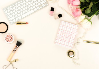 Flat lay women's office desk workplace with flowers. Female workspace with keyboard,  flowers pale pink roses,  gifts, makeup accessories on white background. Top view feminine background.Copy space