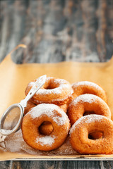 Homemade donuts  with powdered sugar on a wooden baclground