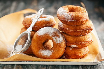 Homemade donuts  with powdered sugar on a wooden baclground