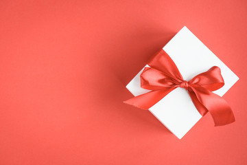 Gift box with red bow on red background.