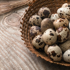 Obraz premium Quail eggs in wicker basket on wooden background