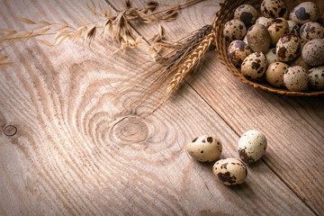 Quail eggs in wicker basket on wooden background