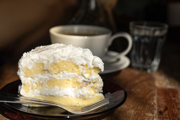 close up piece of coconut chiffon cake on wooden table with warm morning sun light