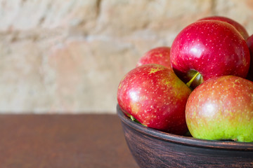 Fresh apples on a metal plate on a brick wall background. Closeup, selective focus