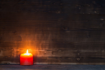Fototapeta na wymiar Burning candle on old wooden background