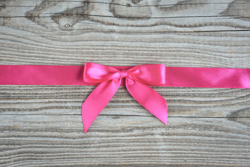 Pink bow on wooden background.