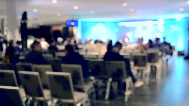 Blurred Background. Many people are sitting in the hall audience listening to presentation lecture speech at forum or conference. Neon lights