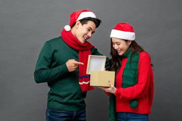 Happy surprised Asian woman opening Christmas gift box given by her boyfriend