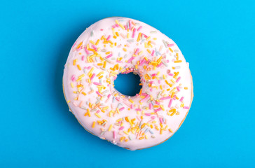 Tasty vanilla donut with sprinkle on bright blue background