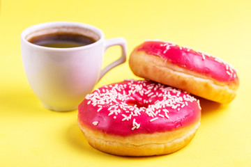 Two delicious pink donuts with sprinkle and cup of coffee