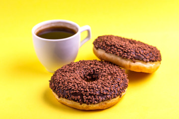 Two delicious chocolate donuts with sprinkle and cup of coffee
