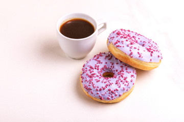 Two delicious lilac donuts with sprinkle and cup of coffee