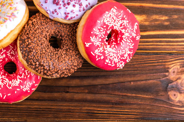 Assorted delicious donuts on rustic wooden background