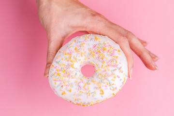 Delicious vanilla donut with sprinkle in woman's hands