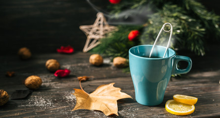 tea in blue cup on wooden table with hot steam. christmas decoration.