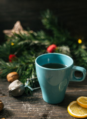 cup of tea on wooden rustic table with christmas decorated blurred pine tree leaves in background