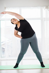 weight loss, healthy lifestyle, sport, activity concept. young overweight woman in sportswear doing stretching exercises to warm up muscles